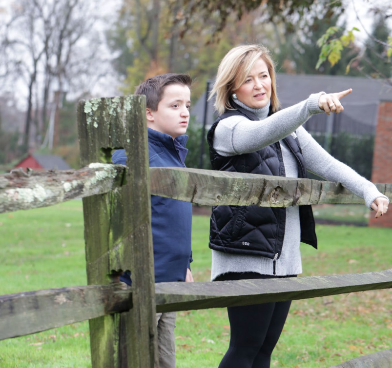 A woman and a boy pointing at a fence, showcasing their rare disease advocacy.